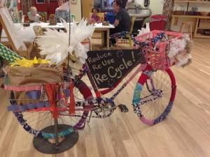 A large room focused on the Arts with several hands on activities (painting, weaving, exploring light, collaging)